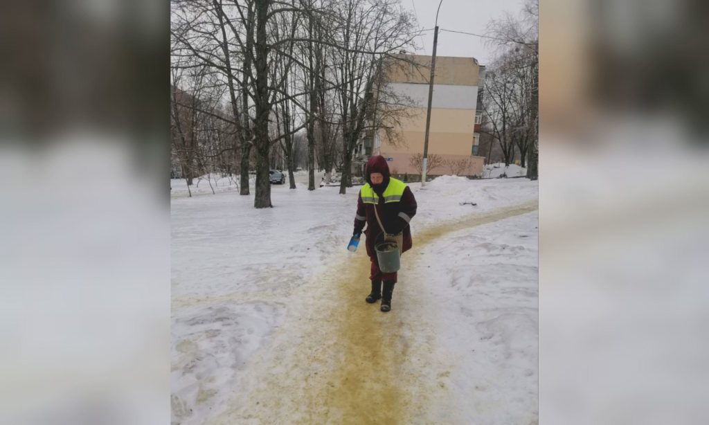 Двірник посипає пісок на ожеледицю