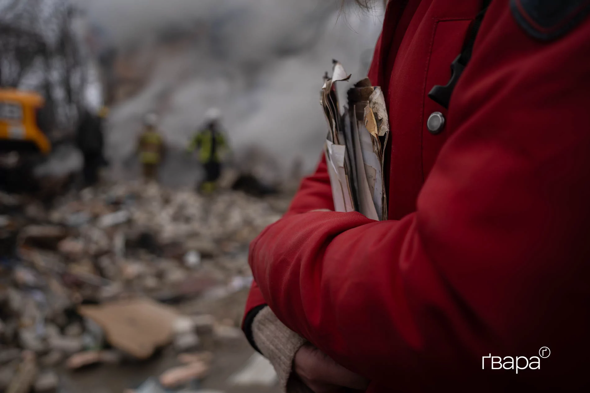 Анна, жителька однієї з квартир у під'зді, зруйнованим російським обстрілом 7 березня. У неї в руках — сімейні фотографії, що порозліталися після обстрілу з її дому. / Фото: Ґвара Медіа, Яна Слємзіна